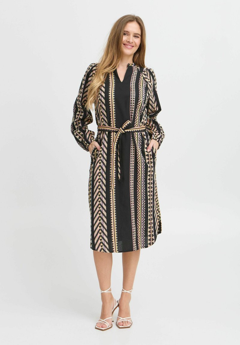 Rochie neagră cu modele geometrice aurii și roz, mâneci lungi, curea cu nod și buzunare laterale; confecționată dintr-un material ușor.