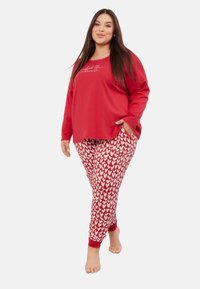 Czerwona bluzka z długim rękawem z napisem "Poczuj miłość"; czerwono-białe spodnie w małe serca; miękki, luźny krój; mankiety na kostkach.