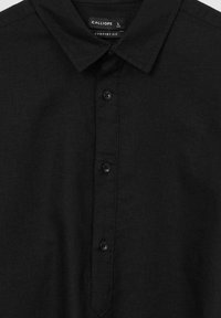 Chemise noire à col, étiquetée Calliope, taille L, coupe confortable, avec quatre boutons visibles sur le plastron avant.