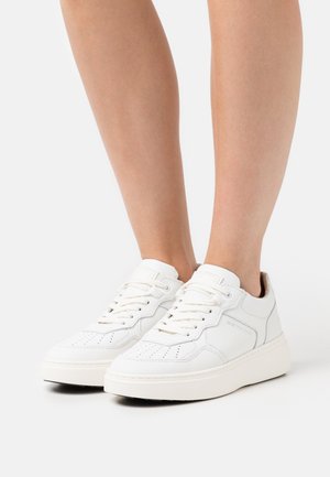 White leather sneakers with a smooth finish, round toe, perforated details, and contrasting light-colored rubber sole. Laces and minimal branding.