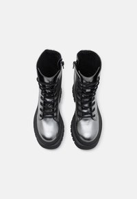 Botas de cuero negro hasta el tobillo con un acabado plateado brillante, que cuentan con punteras redondas, suelas de goma gruesas y un diseño de cordones en la parte delantera.