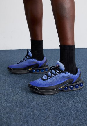 Blaue Mesh-Sneaker mit schwarzen Akzenten, ausgestattet mit einem gepolsterten Kragen, abgerundetem Zehenbereich, schwarzer Gummisohle und markanter, blauer Luftpolsterung.