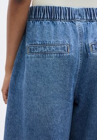 Τζιν σορτς με ελαστική μέση, άνετη εφαρμογή και δύο πίσω τσέπες με αντίθετη γαζιά σε ανοιχτό μπλε ύφασμα.