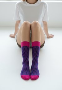 Knæstrømper med pink bølgemønster på navy baggrund, med pink kanter og tå-accenter, båret sammen med en hvid t-shirt.