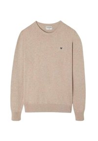 Suéter tejido beige con un cuello redondo, mangas largas, puños acanalados y un pequeño emblema oscuro en el pecho. Textura suave.
