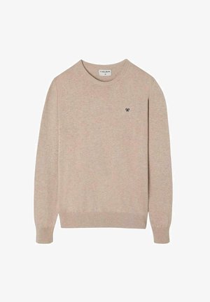 Suéter tejido beige con un cuello redondo, mangas largas, puños acanalados y un pequeño emblema oscuro en el pecho. Textura suave.