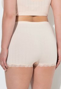 Shorts en mélange de coton beige avec une texture ribbed subtile et une délicate bordure en dentelle à l'ourlet. Conception lisse et ajustée avec une taille mi-haute.