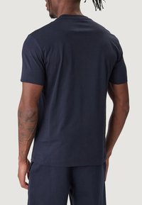 Laivastonsininen puuvillainen t-paita, jossa on lyhyet hihat, pyöreä pääntie ja sileä pinta. Minimalistiset saumat ja normaali istuvuus.