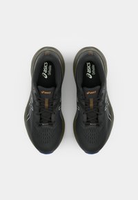 Black athletic shoes with a breathable mesh upper, rubber sole, and white branding, featuring an orange accent on the laces.