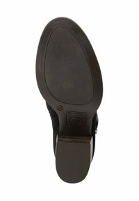 Suola di scarpa in suede nero con grip in gomma testurizzata, tacco leggermente rialzato e bordo liscio. Presenta un'impronta del logo e una forma arrotondata.