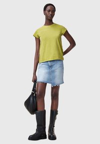 Jasnozielona koszulka z krótkim rękawem, jasnoniebieska spódnica z dżinsu z postrzępionym dołem, czarne kozaki za kolano i czarna torebka na ramię.