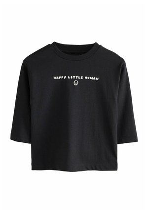 T-shirt nera a maniche corte con testo bianco "HAPPY LITTLE HUMAN" e una piccola faccina sorridente sotto al testo sul davanti.