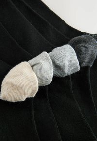 Viis musta soonikkoega sokki, nelja rullitud sokkraanaga beeži, heledahalli, halli ja tumedahalli toonis, järjekorras diagonaalselt.