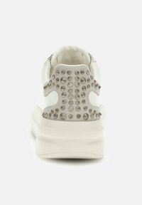 Sneaker bianca con un pannello posteriore grigio testurizzato, caratterizzata da borchie metalliche e una suola spessa bianca. Finitura liscia con colletto imbottito.