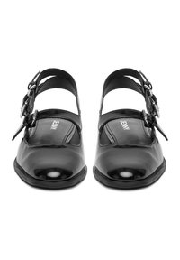 Czarne lakierowane buty typu Mary Jane z okrągłym noskiem, regulowanymi podwójnymi zapięciami na klamry i płaską gumową podeszwą.