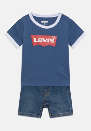 Blå bomulds T-shirt med hvide kanter og rødt Levi's-logo, sammen med denimshorts med slidt finish og synlige syninger.