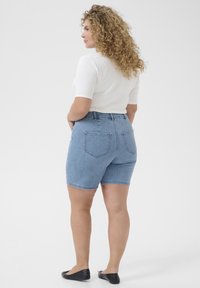 Svetlomodré denim šortky s vysokým pásom, s zadnými vreckami a ohnutým lemom, skombinované s bielou košeľou a čiernymi balerínkami.