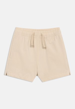 Shorts beiges à taille élastique avec cordon de serrage, poches latérales et petites fentes sur les côtés à l'ourlet.