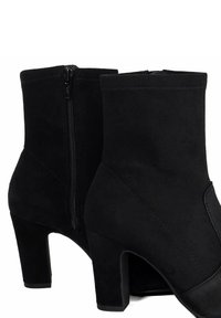 Black faux suede ankle boots with a side zipper, moderate block heel, and stitched detailing on the textured fabric.