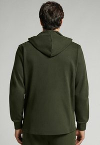 Sudadera color verde oliva oscuro con textura de jersey, que presenta una capucha y mangas largas. Diseño sin costuras con un corte recto en el dobladillo.