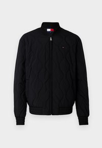 Black quilted bomber jacket with a standing collar, front zip closure, and ribbed cuffs. Features a small logo on the chest.