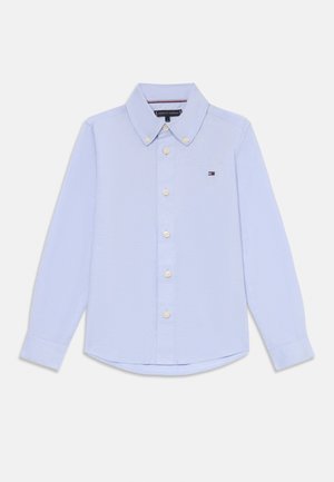 Világoskék, hosszú ujjú, pamut ing, gombos gallérral, fehér gombokkal és egy kis logóval a bal mellrészen.