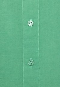 Light green button-up shirt close-up, featuring two round plastic buttons and a smooth, textured fabric with stitching details.