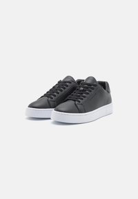 Schwarze Ledersneaker mit glatter Oberfläche, ausgestattet mit einer weißen Gummisohle und schwarzen Schnürsenkeln. Minimalistisches Design mit runder Zehenpartie.