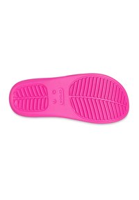 Felle roze Crocs schoenzool met een gestructureerd patroon dat diagonale groeven en ronde indeukingen bevat. Gemarkeerd met "CROCS" en maat "W 7."