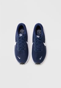 Ναυτικά μπλε αθλητικά παπούτσια Nike με πλέγμα στην επάνω πλευρά, λευκό λογότυπο swoosh και μαύρη σόλα. Διαθέτει στρογγυλά κορδόνια και επενδεδυμένο κολάρο για άνεση.