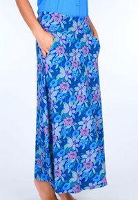 Blumiger knielanger Rock aus blauer Stoff mit lila und pinken Blumen, ausgestattet mit seitlichen Taschen und einem breiten elastischen Bund.