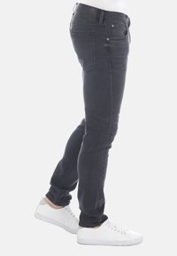 Šedé úzké džíny se středním pasem, s bočními a zadními kapsami. Kombinované s bílými teniskami. Hladká džínová textura.