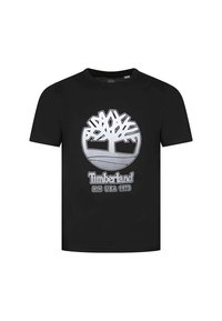T-shirt en coton noir avec un graphique argenté représentant un logo d'arbre, accompagné du texte "Timberland" et "N.H. USA 1973" en dessous. Manches courtes et col rond.