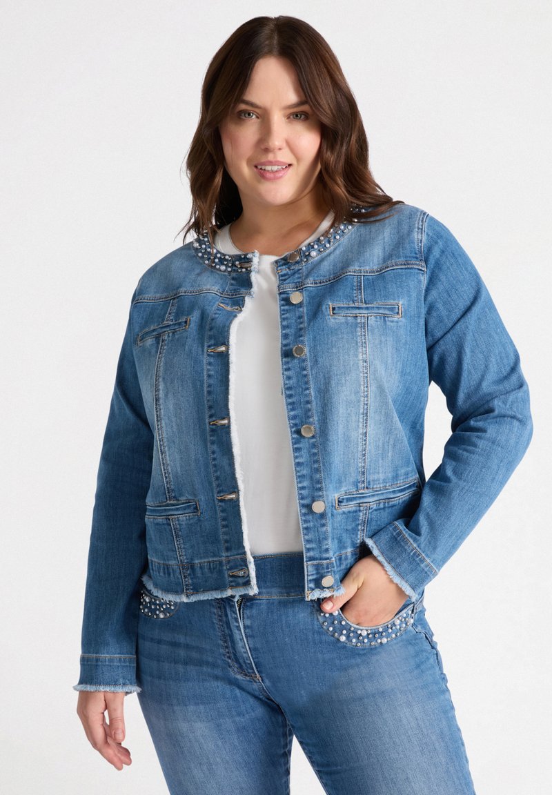 Jeansowa kurtka w średnim niebieskim kolorze z perłowymi akcentami wokół dekoltu, zapięcie na guziki z przodu, dwie kieszenie na piersi oraz postrzępiony dół.