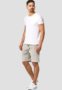 Shorts en coton gris avec taille à cordon et deux poches latérales, associés à un T-shirt blanc à manches courtes uni et des baskets blanches.