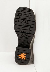 Suela de zapato de goma negra con textura y surcos, y un acento de estrella naranja en el talón.