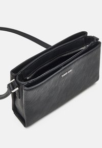 Borsa a tracolla nera con texture, dotata di più scomparti, dettagli in metallo argentato, aperture a zip e una forma rettangolare slim.