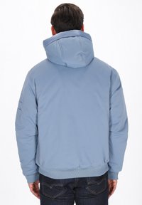 Lys blå hættetrøje med en blød tekstur, quiltet design, ribbede manchetter og kant, samt en lappe-lomme på venstre ærme.