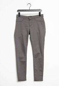 Grijze slim-fit broek met vijf zakken, een knoop- en ritssluiting en een gladde structuur, hangend aan een zwarte plastic haak.