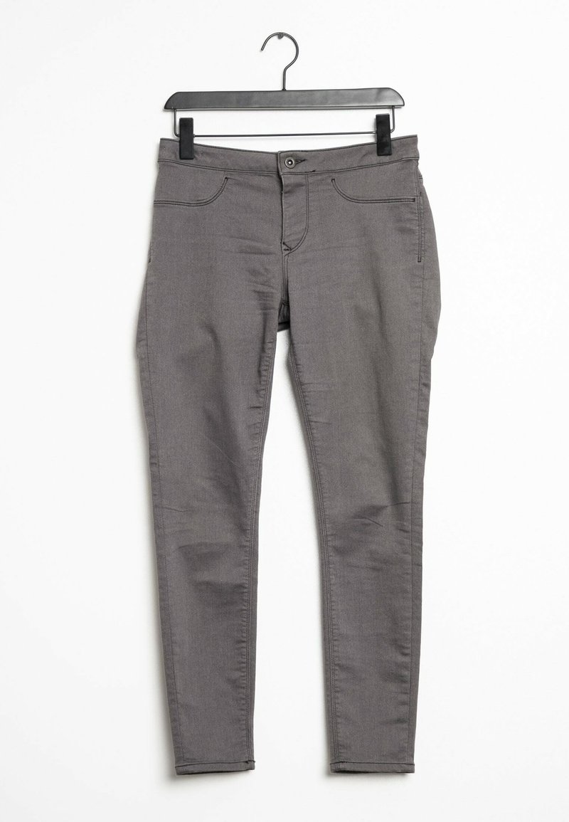 Grijze slim-fit broek met vijf zakken, een knoop- en ritssluiting en een gladde structuur, hangend aan een zwarte plastic haak.