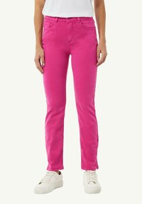 Dopasowane różowe spodnie bawełniane z pięcioma kieszeniami, szlufkami na pasek i prostym krojem, w połączeniu z białymi trampkami.