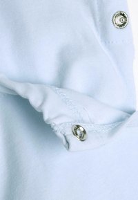 Tessuto blu chiaro con una consistenza morbida, caratterizzato da una chiusura a scatto in metallo argentato e bordi cuciti, che mette in evidenza un'arte manifatturiera dettagliata.