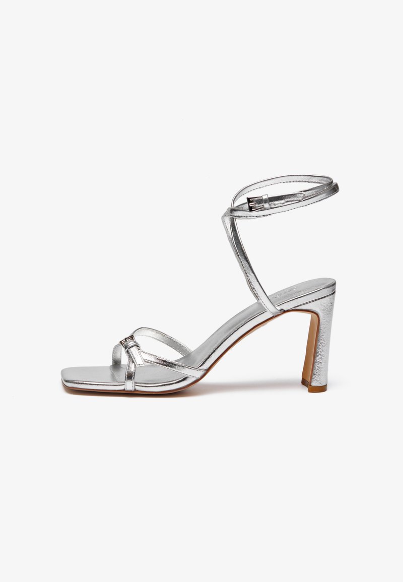 Silver high-heeled sandals with a square toe, thin ankle strap, and vamp straps. Smooth metallic finish with a 3-inch block heel.