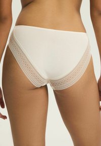 Białe bawełniane majtki z koronkową lamówką. Gładka faktura, umiarkowane krycie oraz misterny wzór koronki na pasku i krawędziach nogawek.