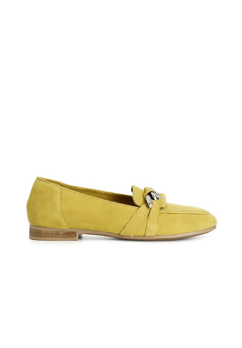 Zapato plano de ante amarillo con punta redonda, que presenta un detalle de tira retorcida y un pequeño acento plateado, montado sobre un bajo tacón de madera.