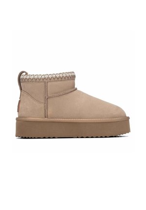 Bota tobillera de ante beige con suela gruesa y ribete de punto alrededor del tobillo sobre un fondo blanco.