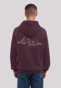 Burgunderfarbene Kapuzenjacke mit Zugkordel, auf der Rückseite mit einem weißen Grafikdesign von Bergen und Bäumen. Weicher Stoff mit elastischen Bündchen und Säume.