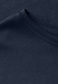 Tela de camiseta de algodón color azul marino, con cuello redondo y textura fina, con costuras visibles a lo largo del cuello y la costura del hombro.