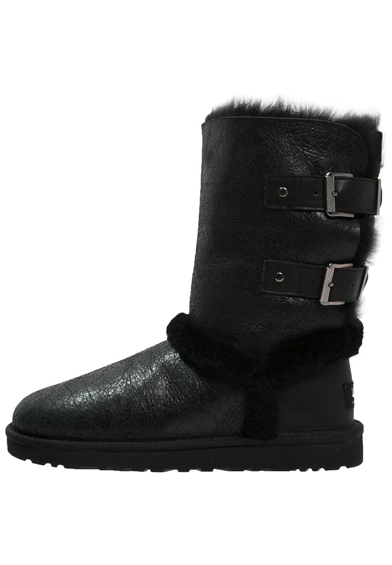 Bottes hautes jusqu'aux genoux en similicuir noir, avec deux boucles décoratives, bordure en fausse fourrure douce et finition texturée. Semelle plate en caoutchouc noir pour un bon maintien.