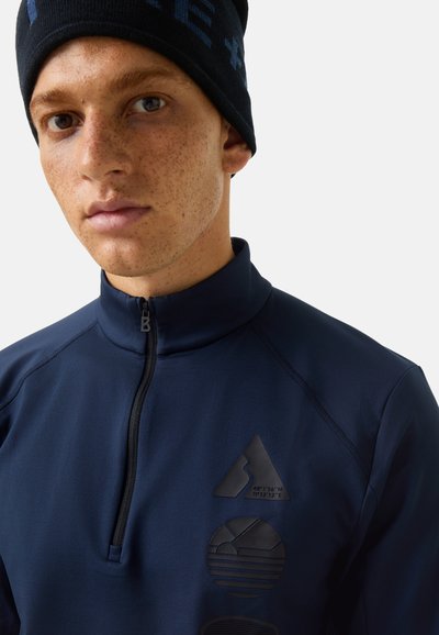 Marineblauer Pullover mit hohem Kragen und halbem Reißverschluss. Mit schwarzen strukturierten grafischen Akzenten: Dreieck, Kreis und geometrische Designs auf der Brust.